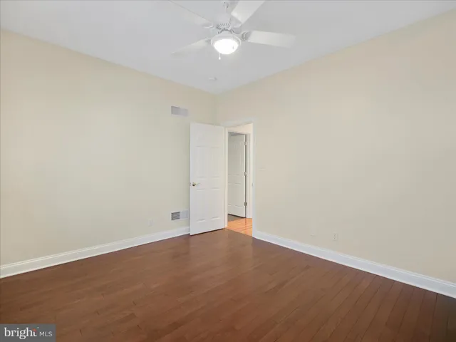 an empty room with wooden floor and fan