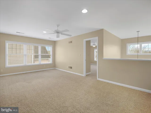 an empty room with windows and chandelier fan