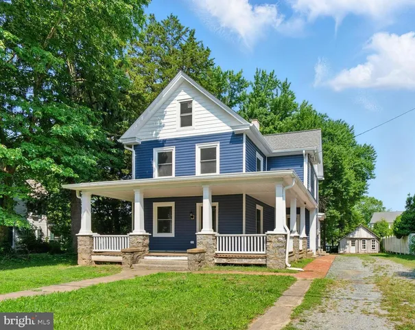 a front view of a house with garden and trees