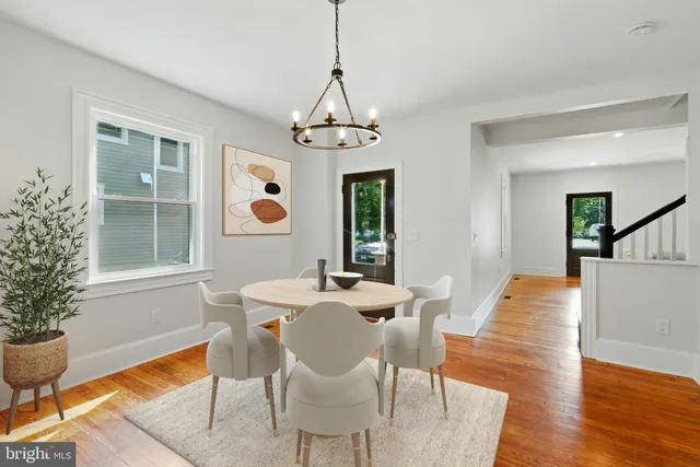 a dining room with wooden floor a chandelier a wooden table and chairs