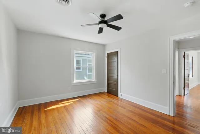 a view of empty room with wooden floor and fan