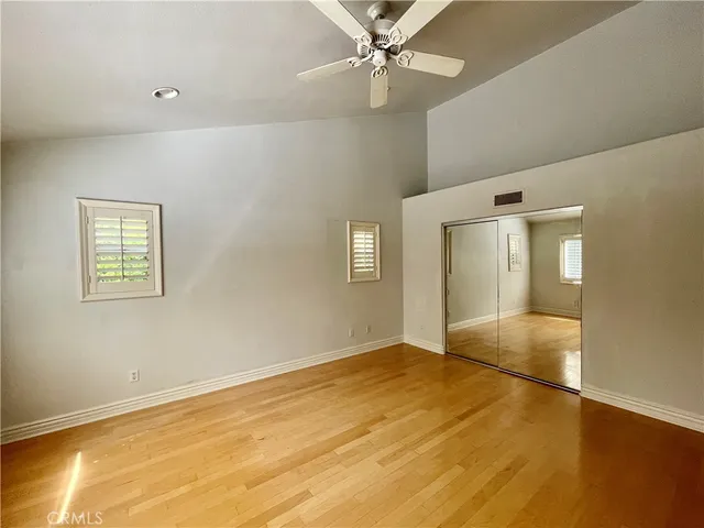 a view of an empty room with wooden floor and a ceiling fan