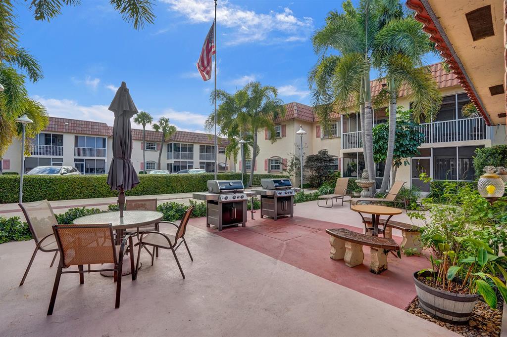 101 East McNab Road, Unit 407 Pompano Beach, FL 33060 - Photo 26 of 29 a view of a patio with couches table and chairs under an umbrella with a fire pit