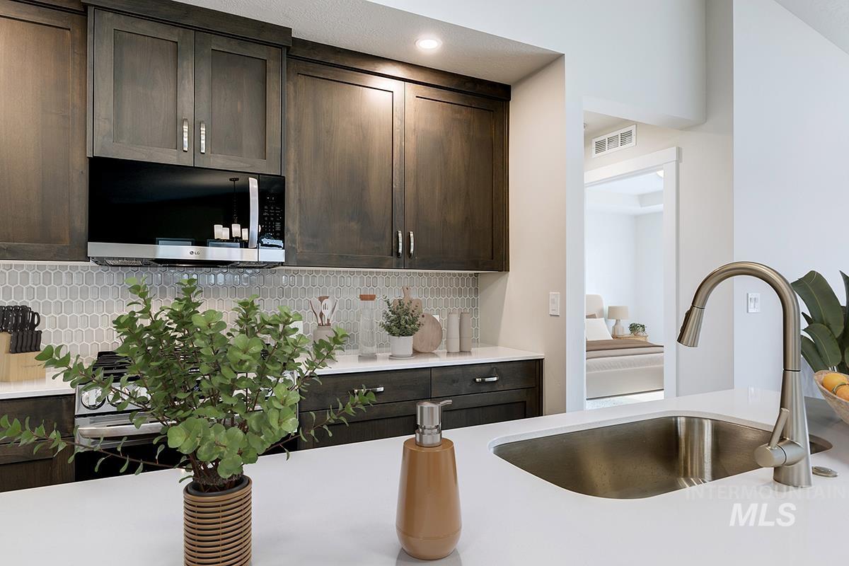 7080 South Gamely Avenue Meridian, ID 83642 - Photo 7 of 30 Kitchen with dark wood finish cabinetry, stainless steel microwave, decorative backsplash, and light stone counters