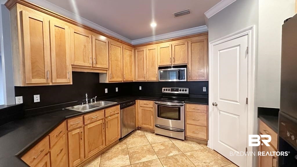 23289 McPhillips Road Loxley, AL 36551 - Photo 4 of 19 Kitchen featuring light wood cabinetry, dark countertops, stainless steel appliances, and tile flooring