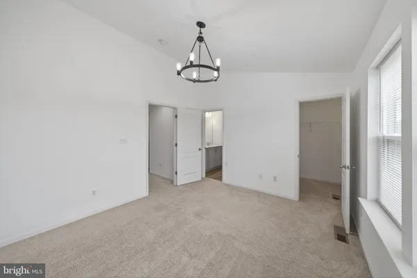 a view of an empty room with wooden floor and window