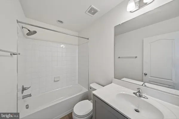 a bathroom with a bathtub shower sink vanity mirror and toilet