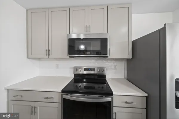 a kitchen with stainless steel appliances granite countertop white cabinets and a stove a refrigerator with white cabinets