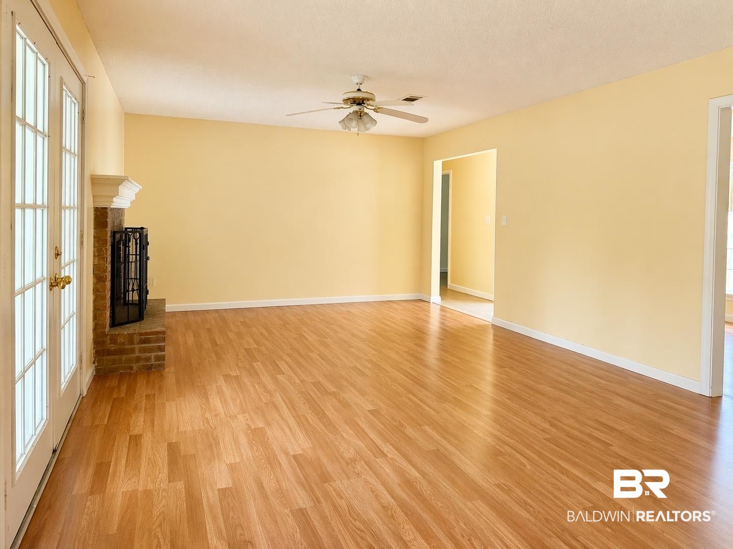 294 Wolf Log Road Flomaton, AL 36441 - Photo 4 of 14 Unfurnished living room with light wood-style floors, a ceiling fan, and a brick fireplace