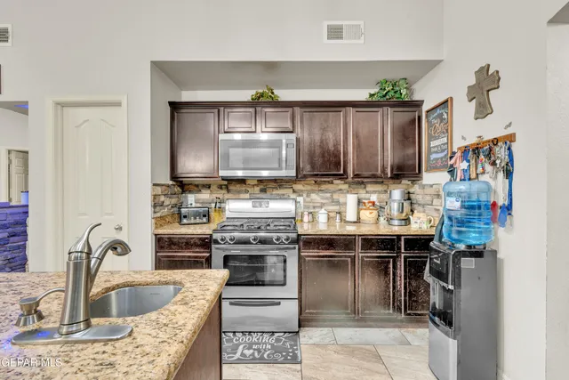 a kitchen with stainless steel appliances granite countertop a sink stove and refrigerator