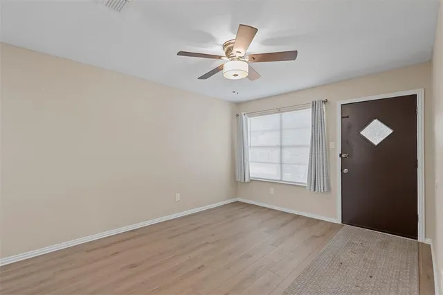 an empty room with wooden floor fan and windows