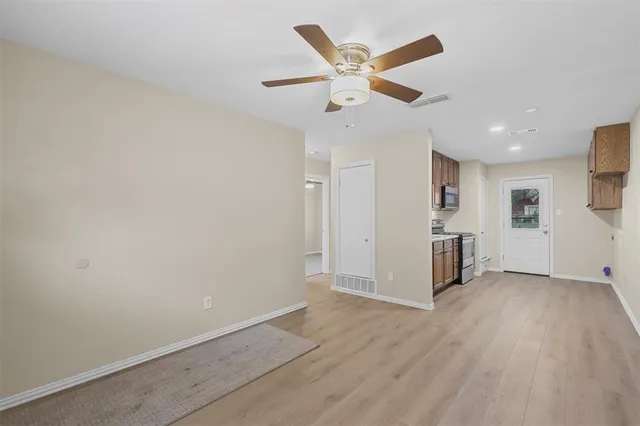 an empty room with wooden floor a ceiling fan and windows