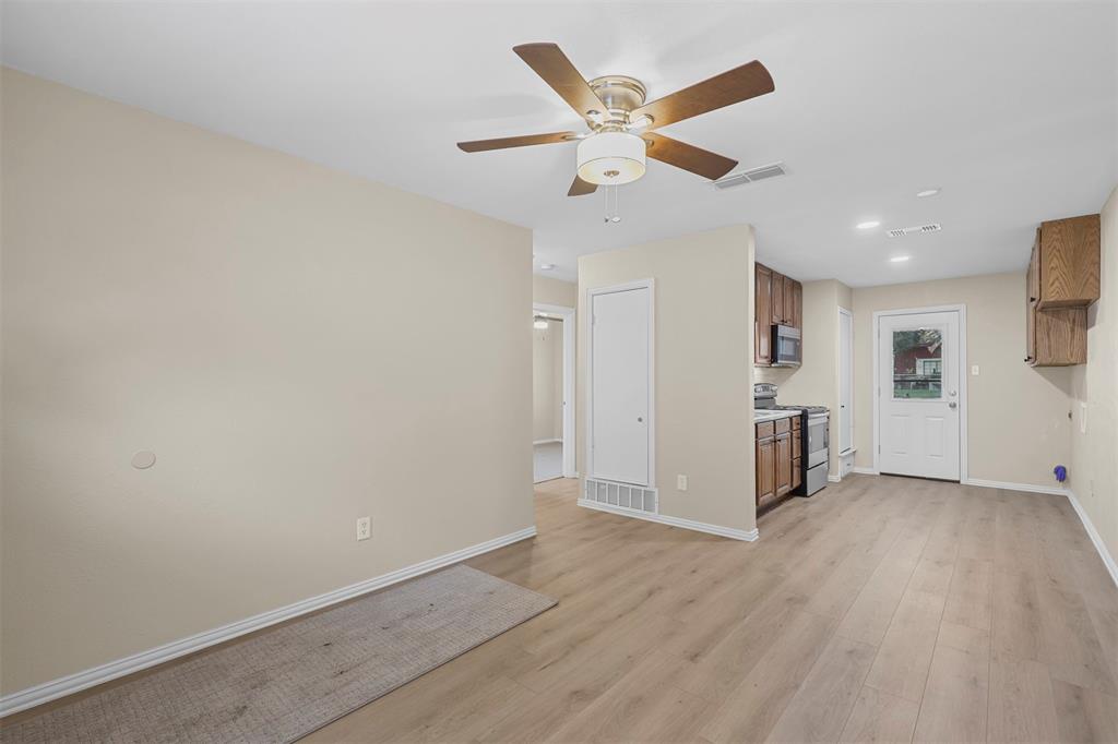 2801 Skyline Drive, Unit A Sansom Park, TX 76114 - Photo 5 of 16 an empty room with wooden floor a ceiling fan and windows