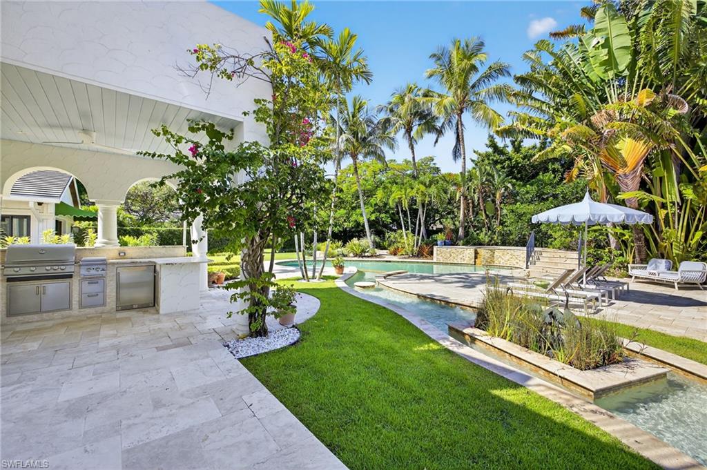 111 Caribbean Road Naples, FL 34108 - Photo 5 of 50 a view of a swimming pool with a table and chairs under an umbrella