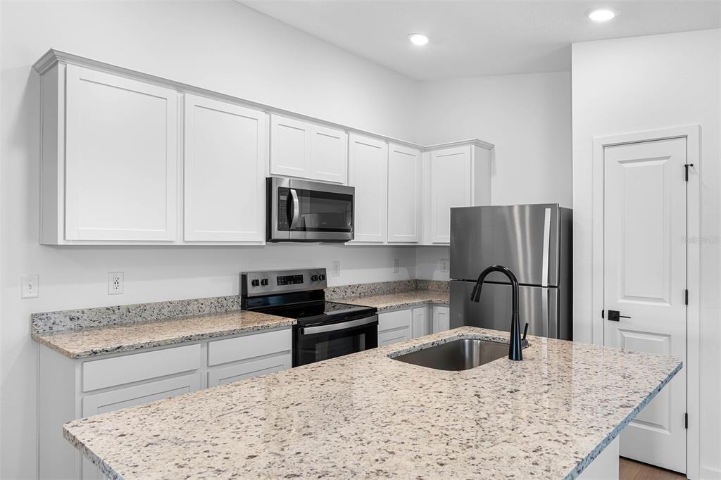 10405 Timbercrest Road Spring Hill, FL 34608 - Photo 5 of 14 a kitchen with stainless steel appliances granite countertop a sink stove and refrigerator