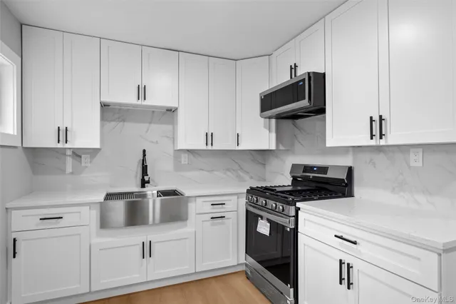 a kitchen with stainless steel appliances granite countertop white cabinets sink and stove