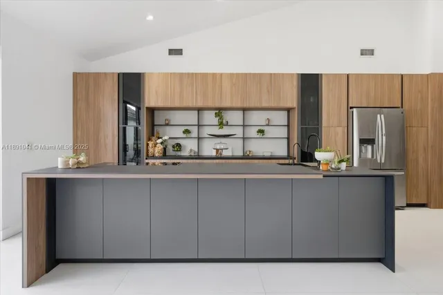 a large kitchen with stainless steel appliances a large counter top a stove and a refrigerator