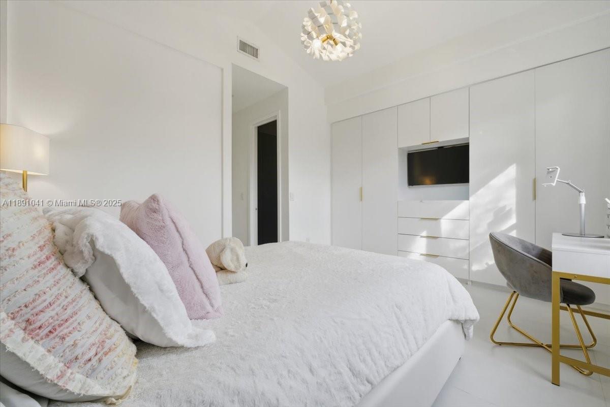 1441 154th Avenue Pembroke Pines, FL 33027 - Photo 30 of 37 a bedroom with a bed tv and a chandelier