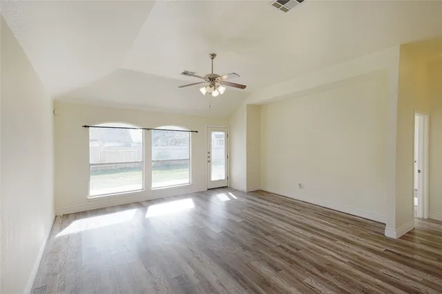 an empty room with wooden floor and windows