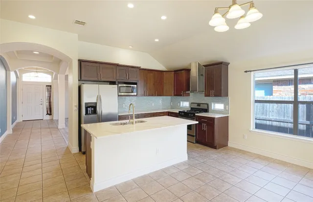 a large kitchen with stainless steel appliances granite countertop a large counter top a sink and a refrigerator