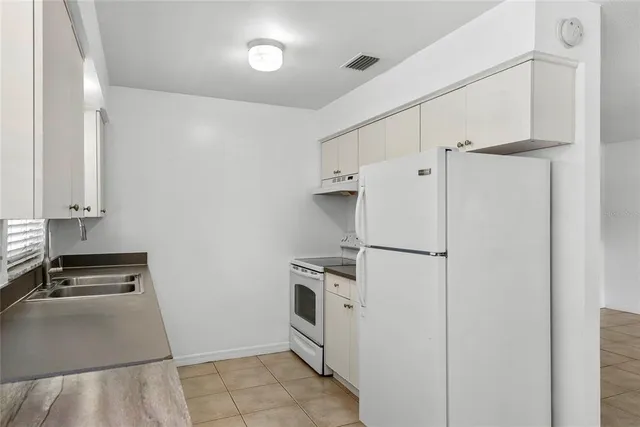 a white refrigerator freezer and a stove sitting inside of a kitchen