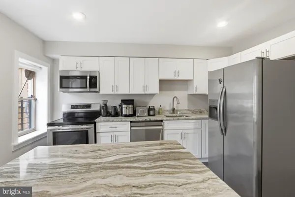 a kitchen with granite countertop a refrigerator stove and microwave