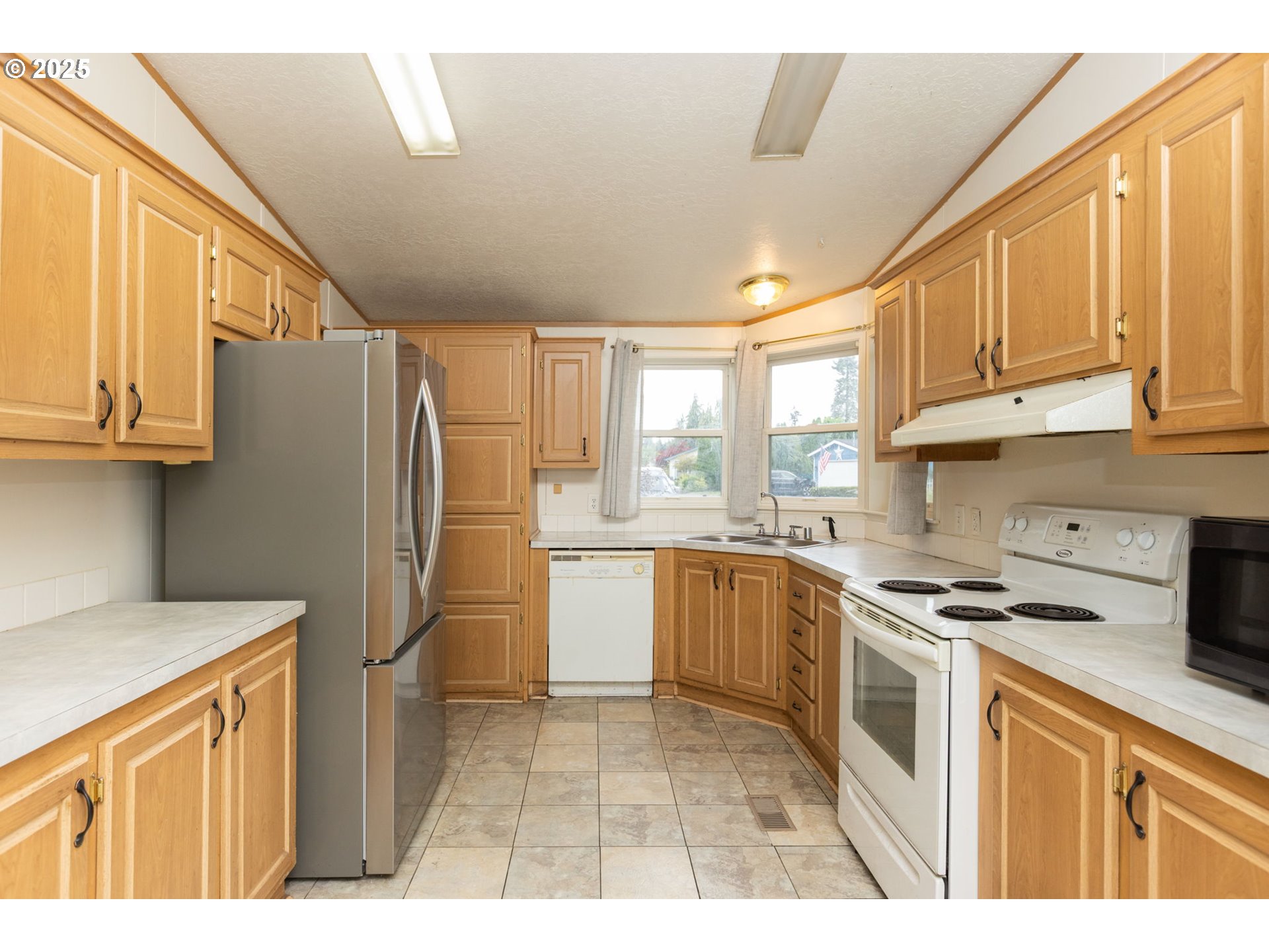 1655 South Elm Street Canby, OR 97013 - Photo 9 of 32 a kitchen with stainless steel appliances granite countertop a refrigerator a sink dishwasher and white cabinets with wooden floor