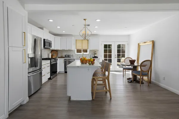a living room with stainless steel appliances furniture a dining table and chairs