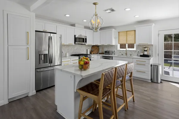 a kitchen with a refrigerator a stove a sink and white cabinets with wooden floor