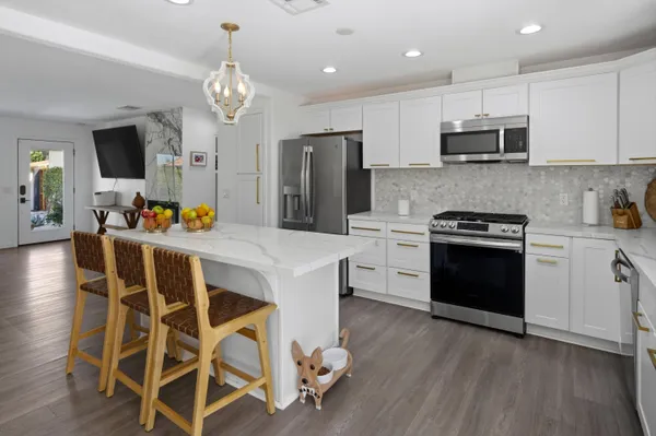 a kitchen with stainless steel appliances granite countertop a stove a sink dishwasher a microwave oven with a dining table and chairs