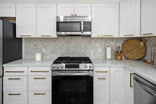 a kitchen with stainless steel appliances granite countertop white cabinets and a stove a oven with white countertops