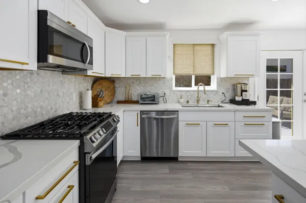 a kitchen with stainless steel appliances a sink dishwasher a stove microwave and cabinets