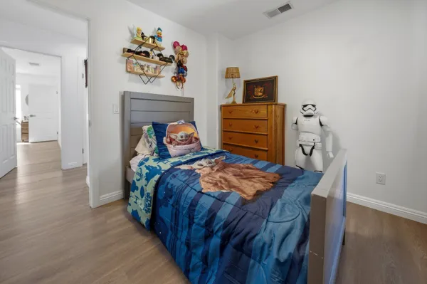 a bedroom with a bed dresser and wooden floor