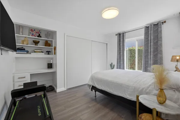 a bedroom with a bed and a flat tv screen on dresser