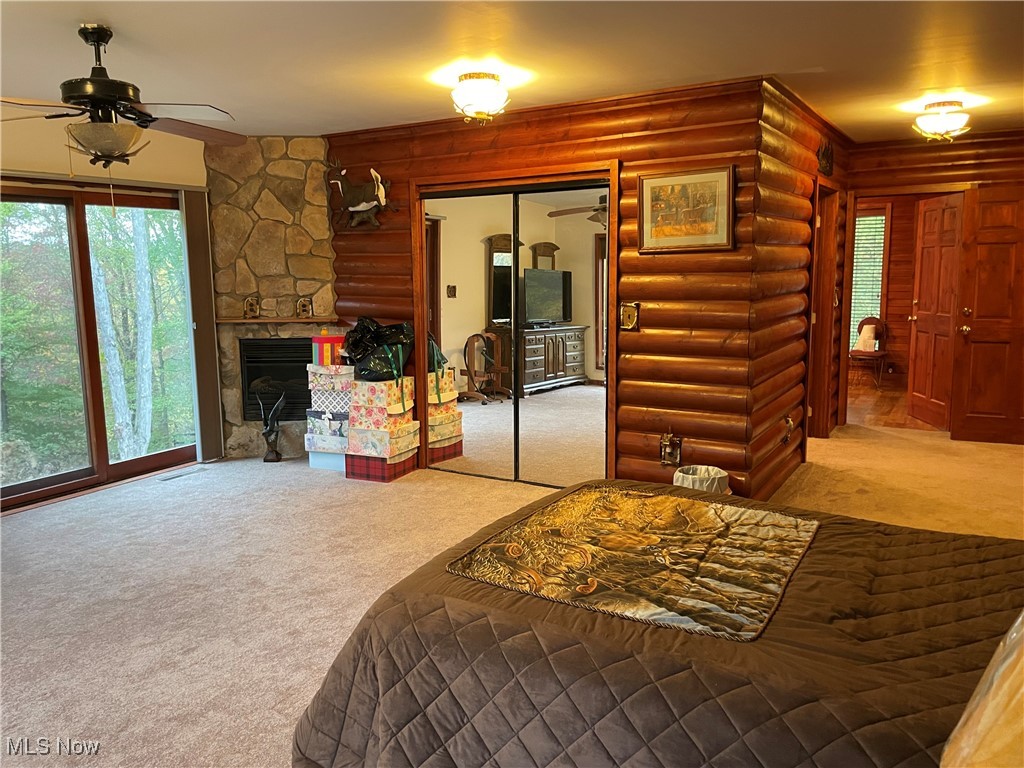 74068 Lake Ridge Road Piedmont, OH 43983 - Photo 20 of 45 Carpeted bedroom with ceiling fan, a fireplace, a closet, and log walls