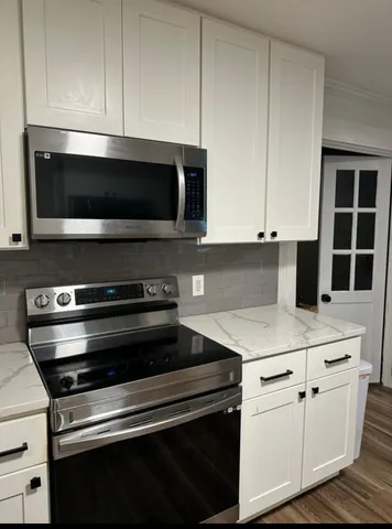 a kitchen with white cabinets and black appliances
