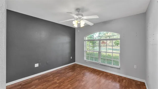 an empty room with a chandelier fan and windows
