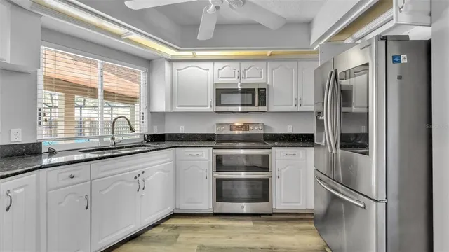 a kitchen with stainless steel appliances granite countertop a sink a stove and cabinets