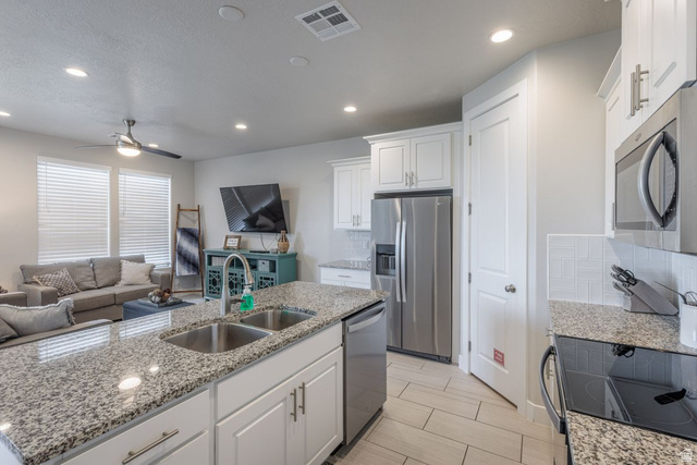 4845 Fishers Is Way St. George, UT 84770 - Photo 41 of 41 Kitchen with white cabinets, appliances with stainless steel finishes, open floor plan, tasteful backsplash, and light stone countertops
