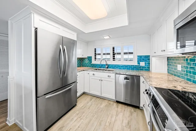 a large white kitchen with granite countertop a refrigerator and a sink