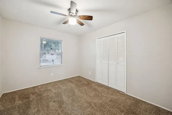 an empty room with closet and a ceiling fan
