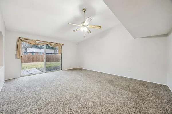 an empty room with windows and ceiling fan