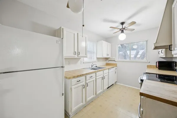 a kitchen with a refrigerator a sink and dishwasher with white cabinets
