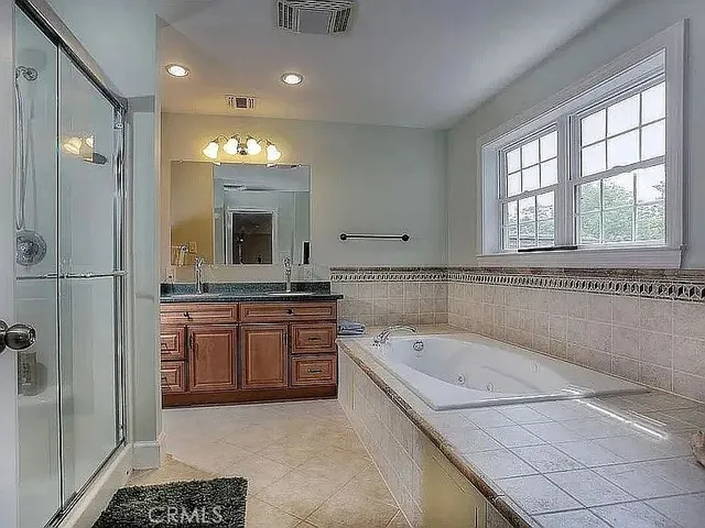 a spacious bathroom with a tub sink and mirror