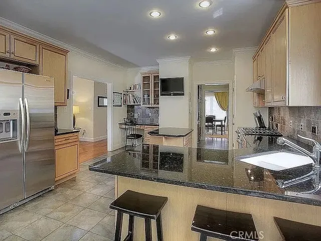 a kitchen with kitchen island granite countertop a sink refrigerator and cabinets