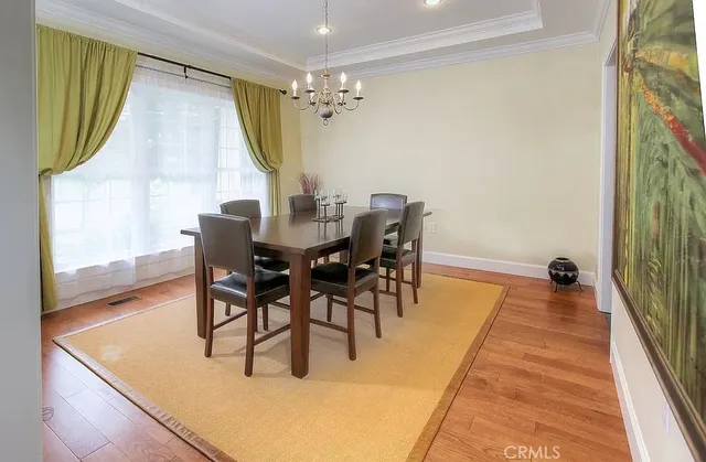 a dining room with chandelier and wooden floor