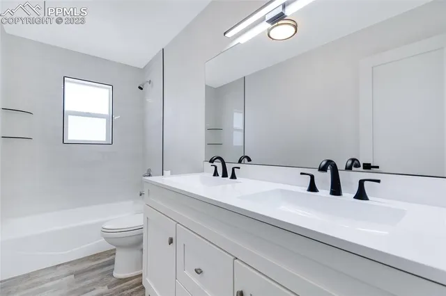 a bathroom with a double vanity sink toilet a tub and a mirror