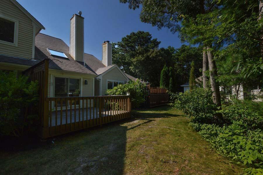 3 Kettle Lane Mashpee, MA 02649 - Photo 23 of 27 a view of a brick house with a small yard and wooden fence