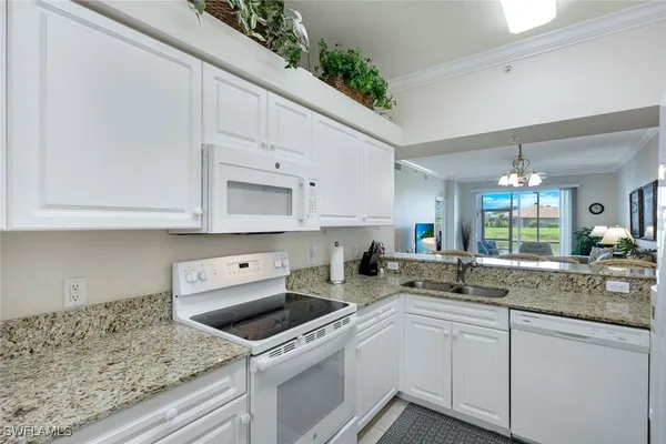 a kitchen with granite countertop a sink stainless steel appliances white cabinets and a window