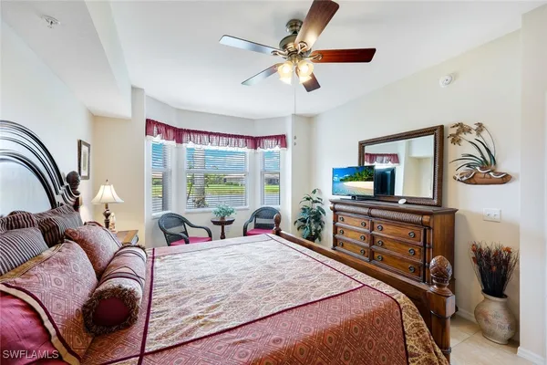 a bedroom with a bed a couch and a flat tv screen on dresser